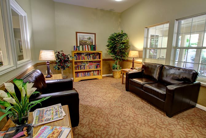 A cozy waiting room with sofas, a bookshelf, and warm lighting.