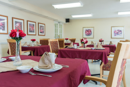 A beautifully arranged dining area featuring red tablecloths and floral centerpieces, ready for guests.