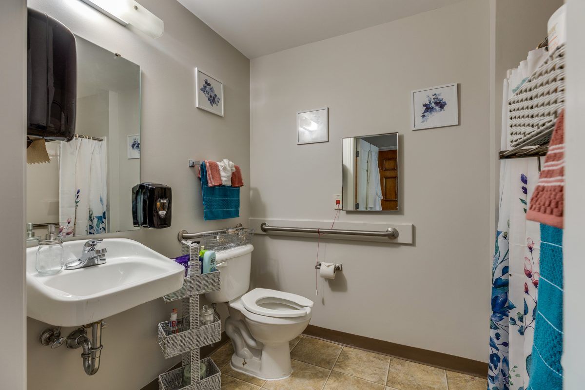A well-organized bathroom with a toilet, sink, and handrail.