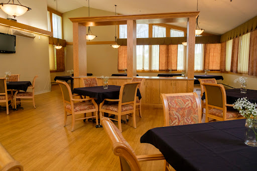 A spacious dining area featuring wooden furniture and large windows that allow natural light to fill the room.
