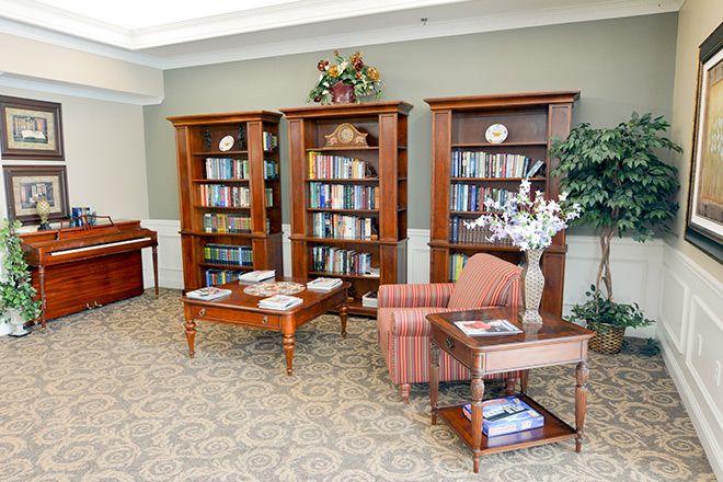 A cozy library reading area featuring bookshelves, comfortable chairs, and a piano.