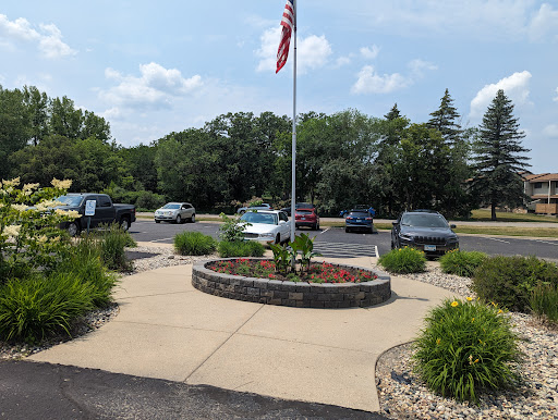 A peaceful outdoor area featuring an American flag and a landscaped circular garden in a parking lot.