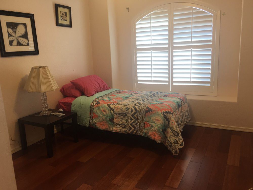 A cozy bedroom with a single bed, colorful bedding, and wooden flooring.