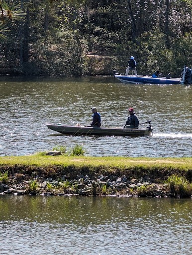 Two people enjoy a day on the water in a small boat while another boat is visible in the background.