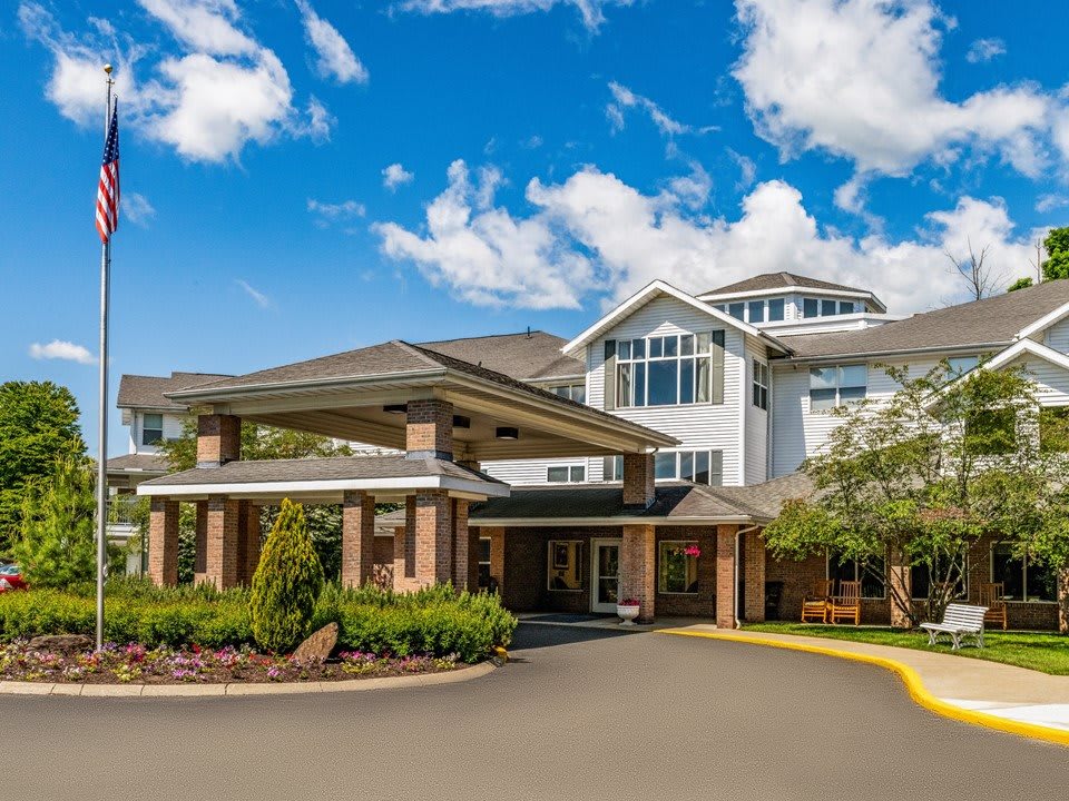 A multi-story residential building with a landscaped entrance under a bright blue sky.