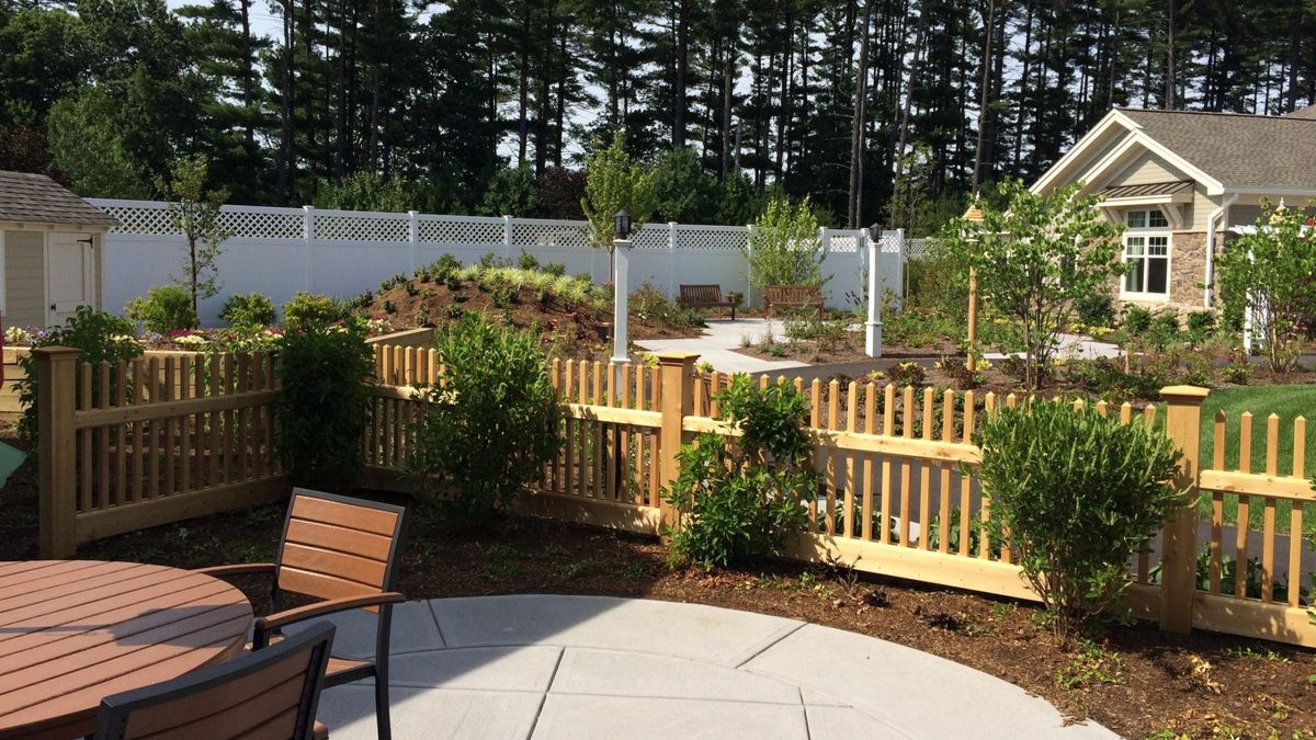 A serene garden patio with wooden fencing and lush greenery.
