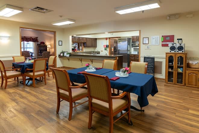 A cozy dining area with tables set next to an open kitchen space.