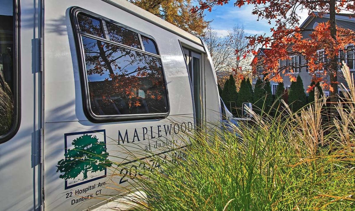 A Maplewood van is parked outdoors, surrounded by autumn foliage.