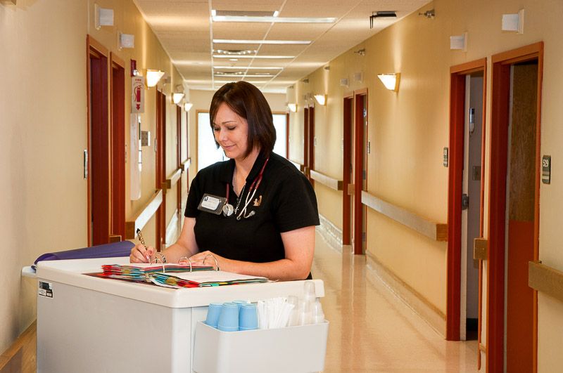 A nurse writing notes at a workstation in a hospital corridor.
