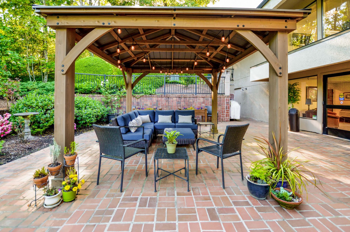 A cozy outdoor patio with a pergola, featuring comfortable seating and ambient string lights.