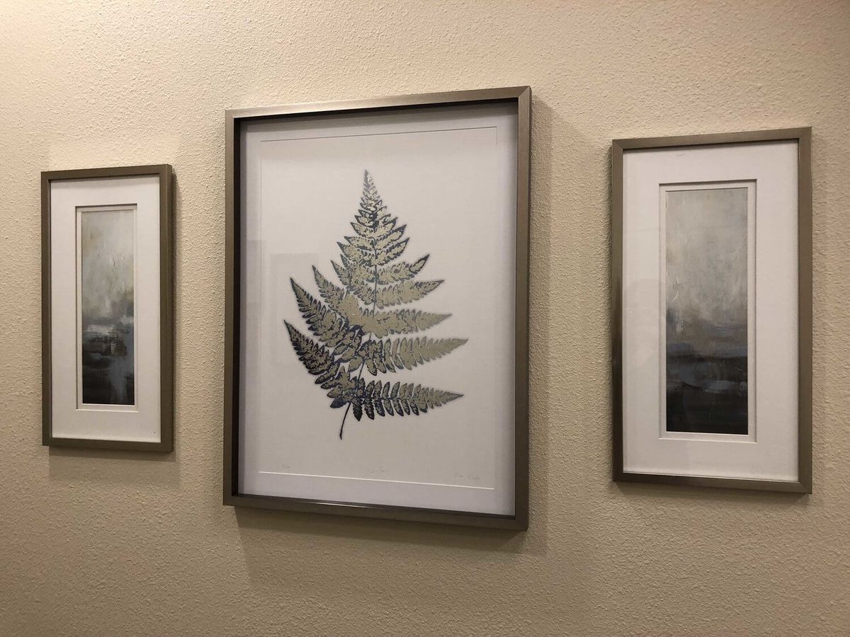 Framed fern artwork displayed on a wall alongside other framed pieces.