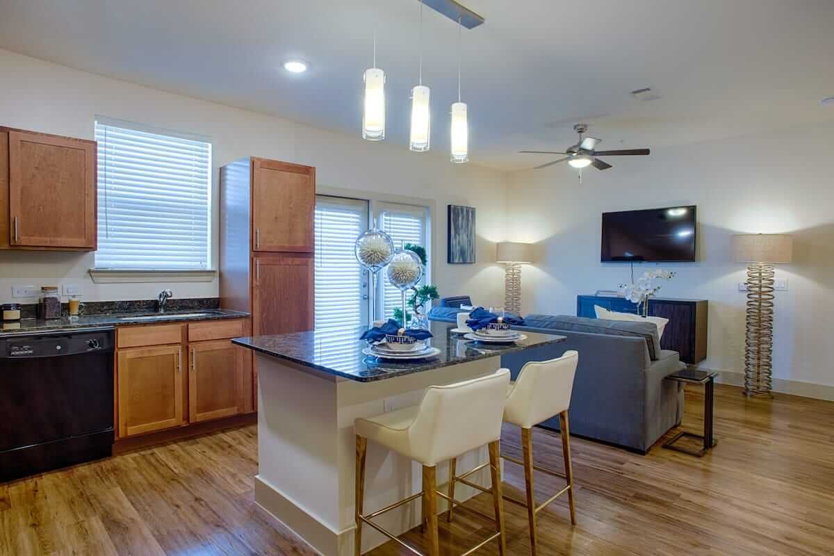 A modern open concept living space featuring a kitchen with an island and bar stools, adjacent to a cozy living area.