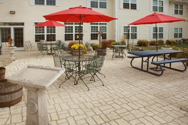 Outdoor patio with tables, chairs, and red umbrellas.