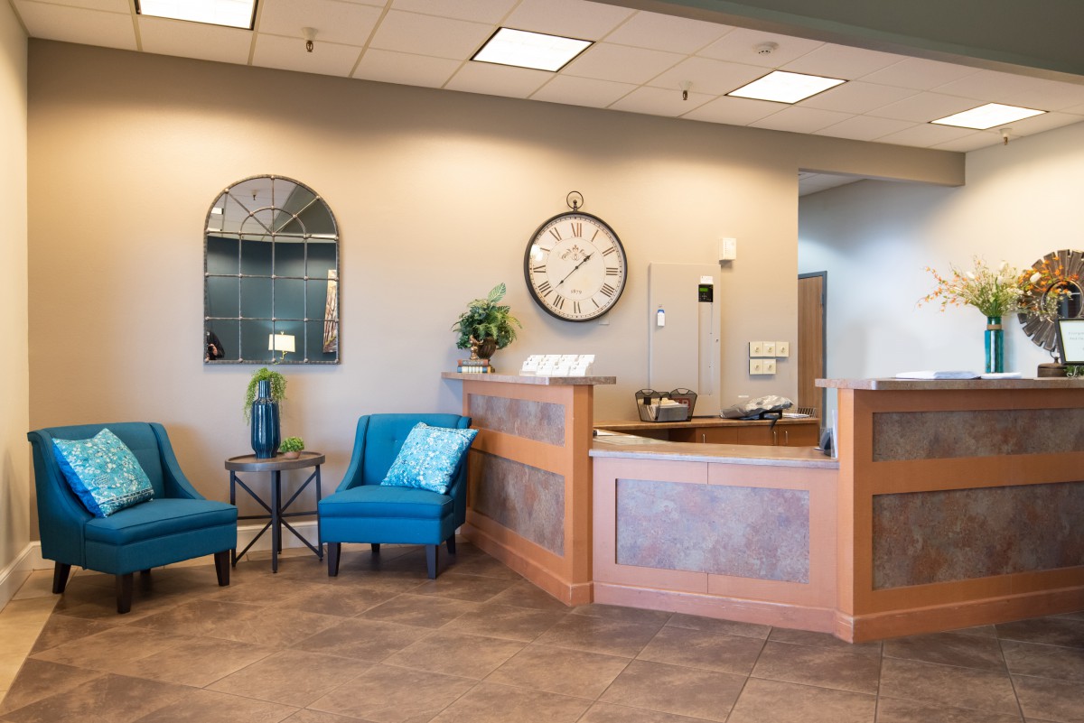 A welcoming reception area with blue chairs and a large wall clock.
