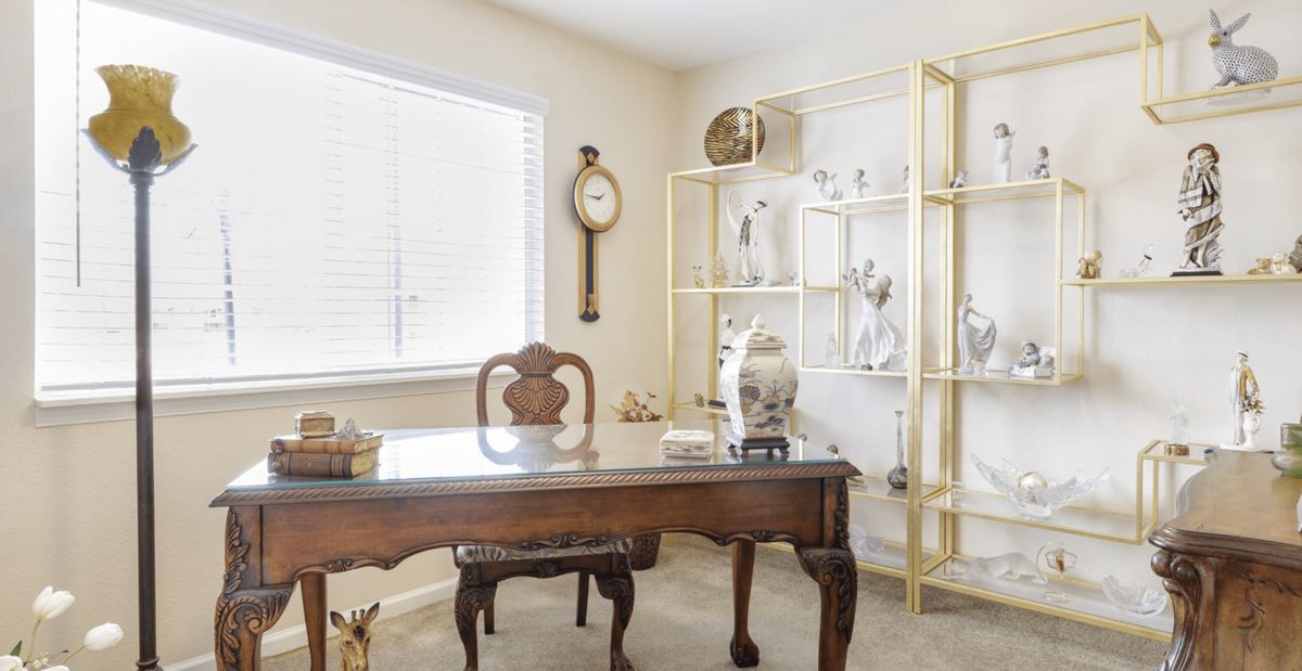 A bright home office featuring a wooden desk and decorative shelves.