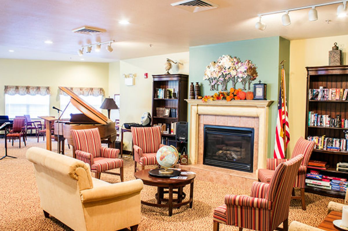 A cozy living room with a fireplace, seating area, and piano.