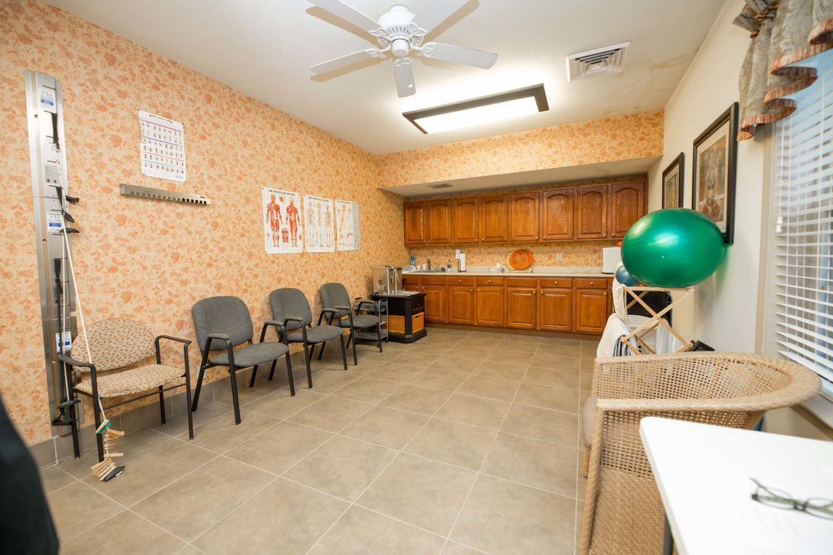 A clean waiting room in a clinic with several chairs and anatomical posters on the wall.