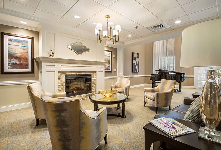 A cozy and elegantly designed living room with a fireplace, armchairs, and a piano.
