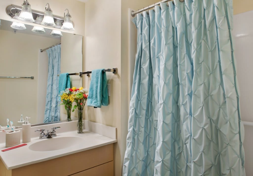A cozy bathroom with a light blue shower curtain and matching towels.