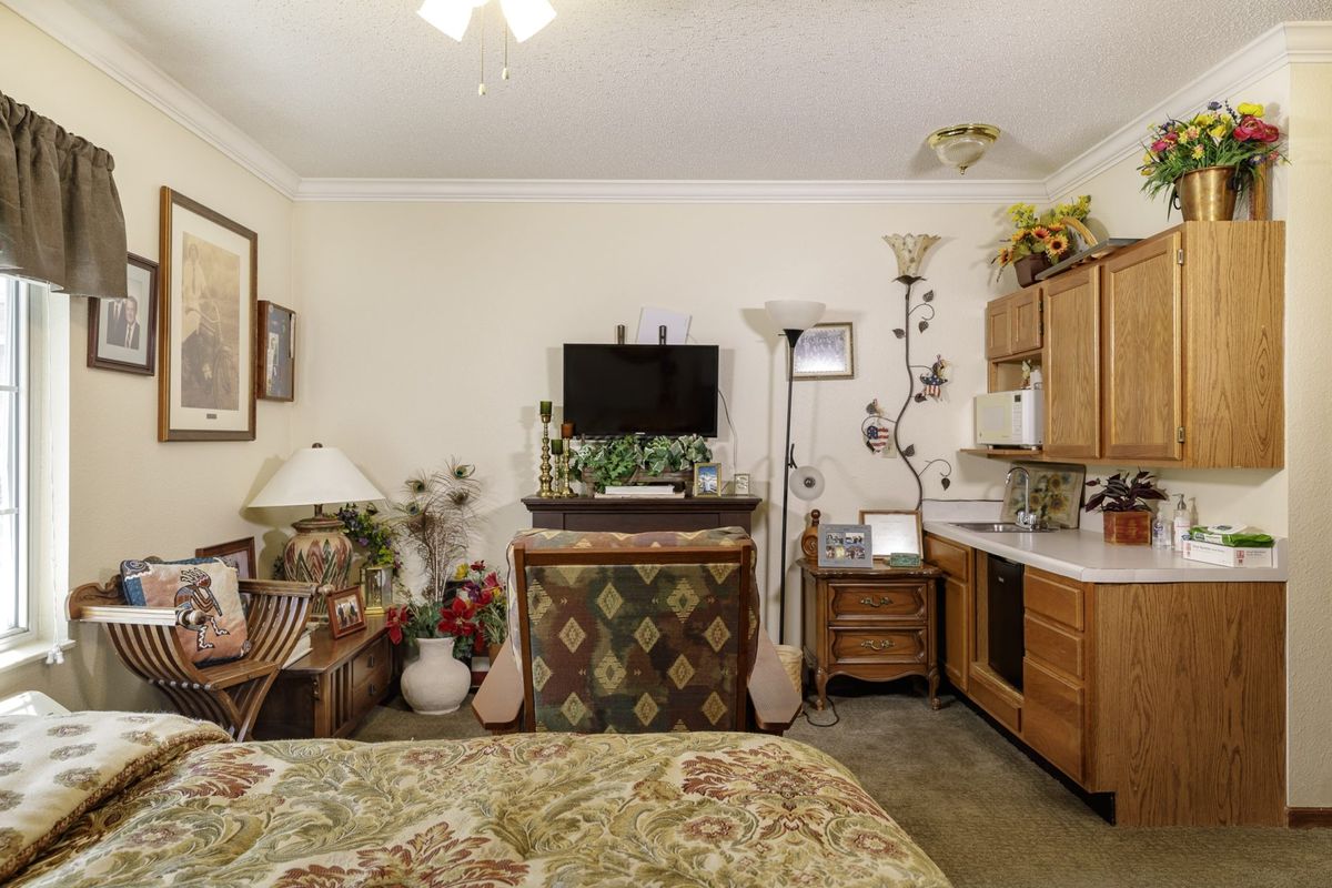 A cozy bedroom with a television, floral bedspread, and assorted decor.
