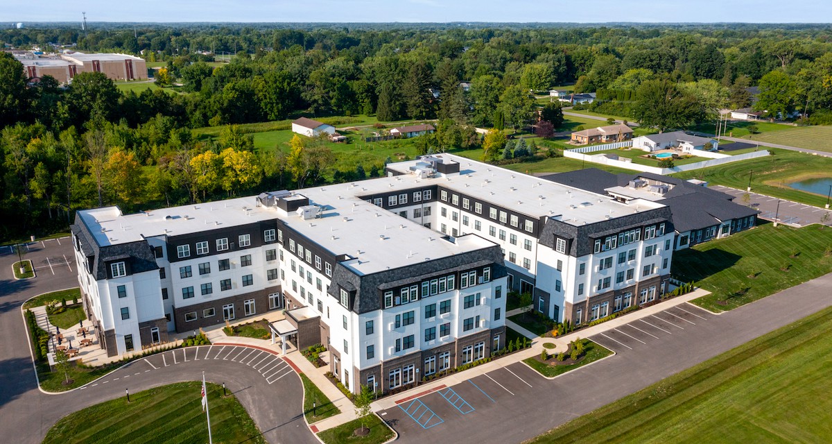 Aerial view of a modern residential complex surrounded by greenery in a suburban area.