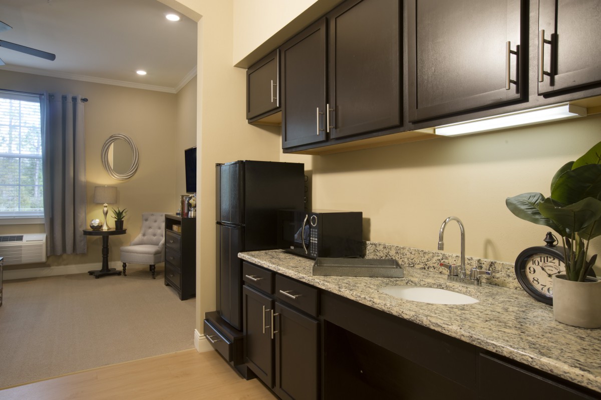 A modern apartment kitchen with dark cabinets and granite countertops.