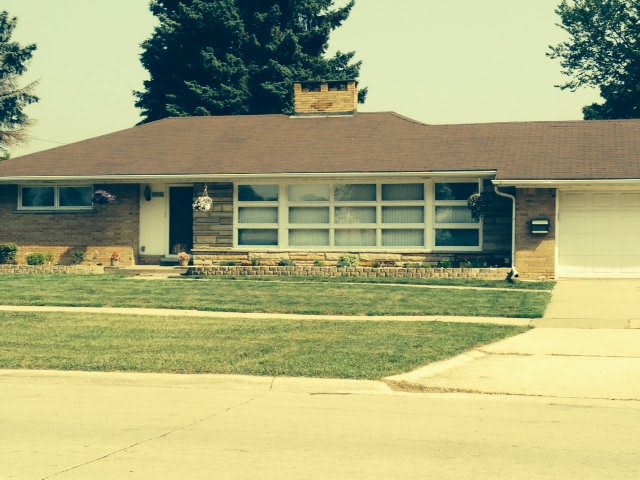 A suburban single-story house with a well-maintained lawn and driveway.