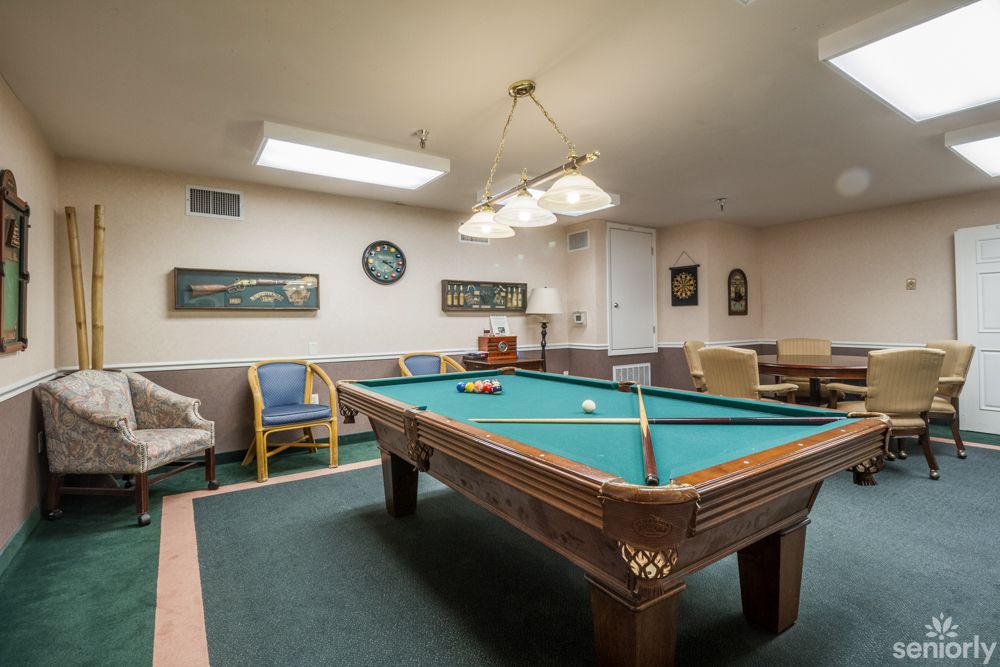A cozy billiard room with a pool table and comfortable seating.