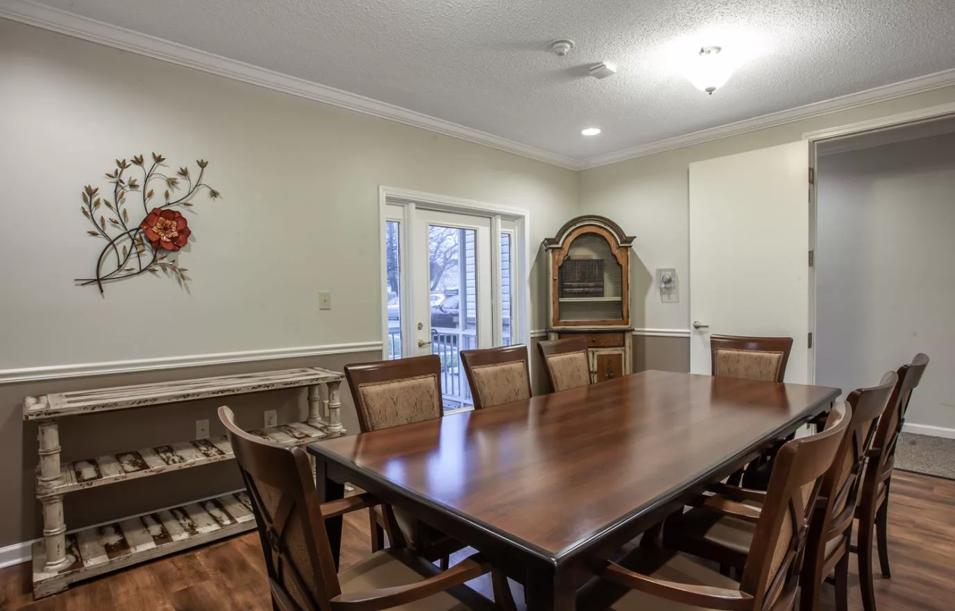 A cozy dining room with a wooden table, surrounded by chairs, featuring elegant interior decor.