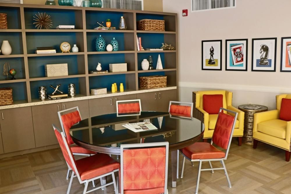 A modern dining area with colorful chairs and a large bookshelf filled with decorative items.