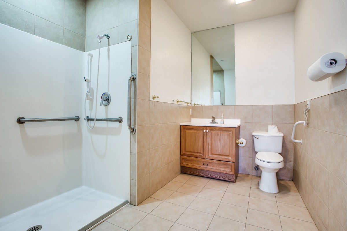 A spacious bathroom with a walk-in shower, wooden vanity, and toilet.