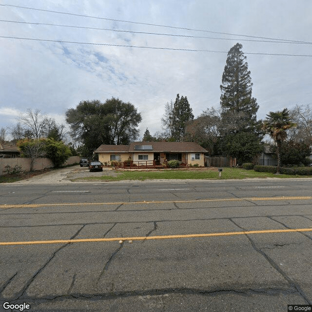 A suburban house located across a wide street on a cloudy day.