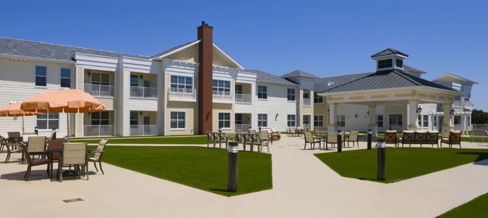 A modern residential building with a well-maintained lawn and outdoor seating area.