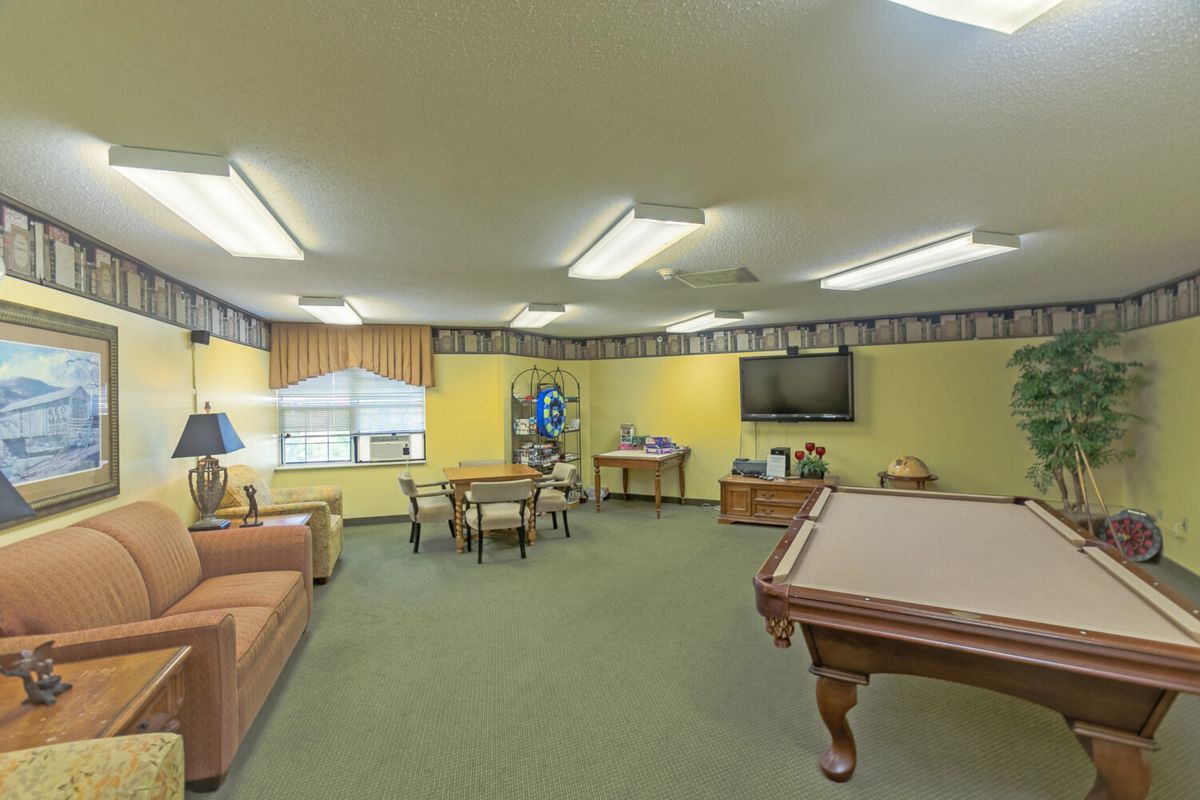 A spacious game room featuring a pool table, comfortable seating, and a television.