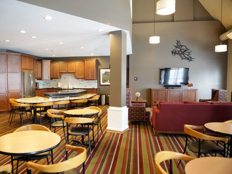A modern dining and living area with wood furniture and a striped carpet.