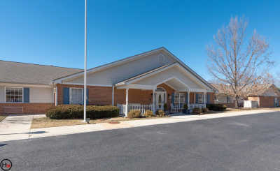 A brick building with a covered entrance and a flagpole, under a clear blue sky.