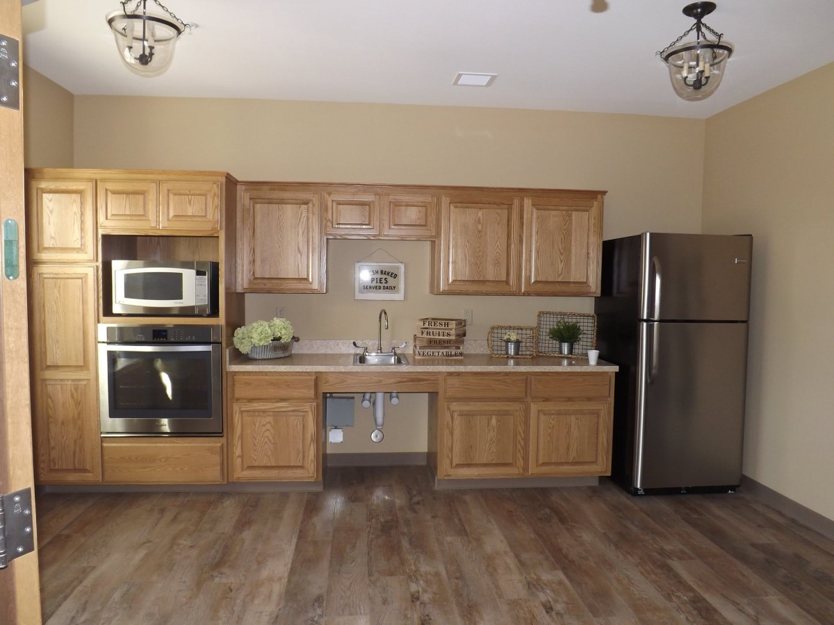 A modern kitchen with wooden cabinets, a stainless steel refrigerator, and built-in appliances.