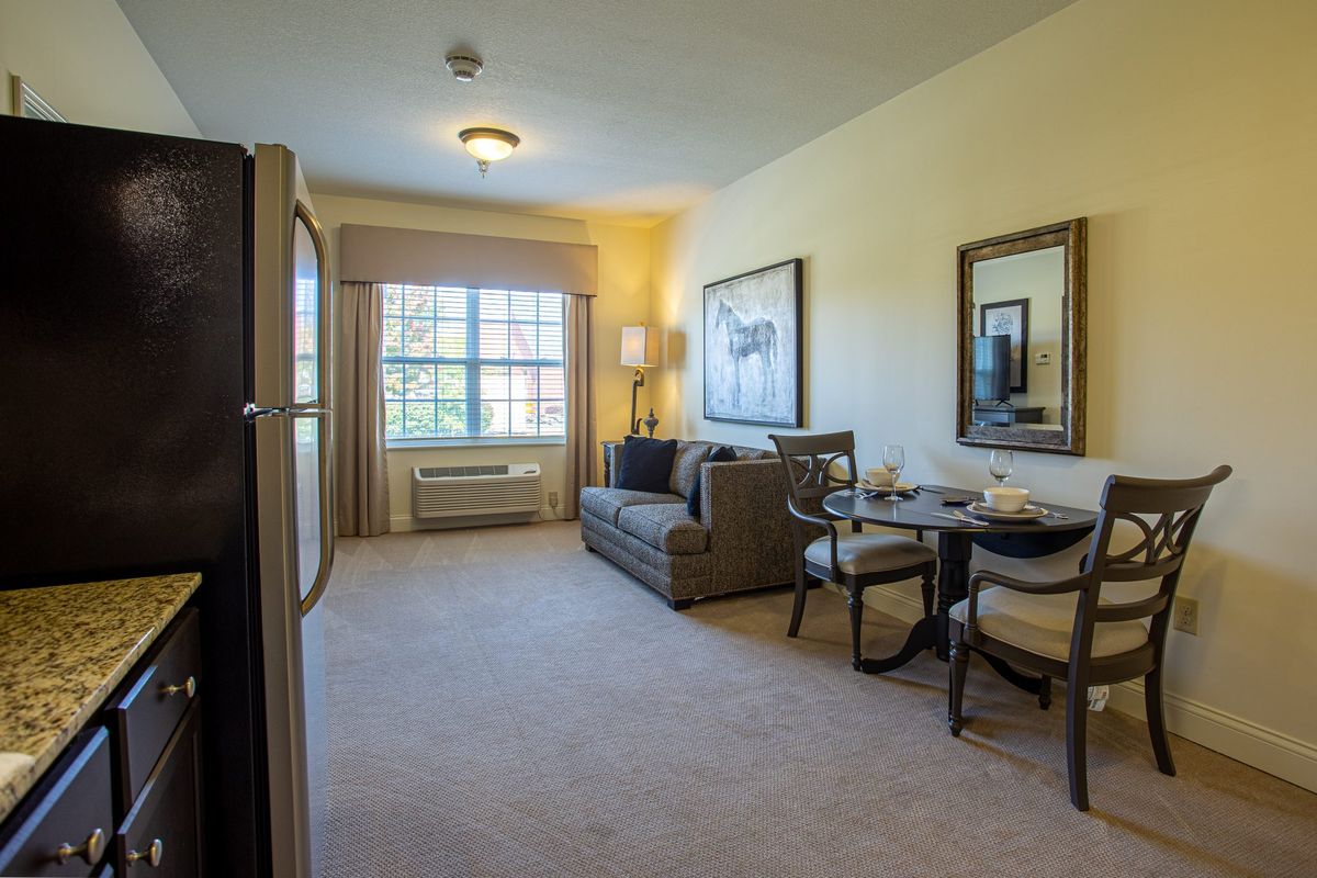 A cozy living room with a sofa and dining area, featuring large windows and elegant wall art.