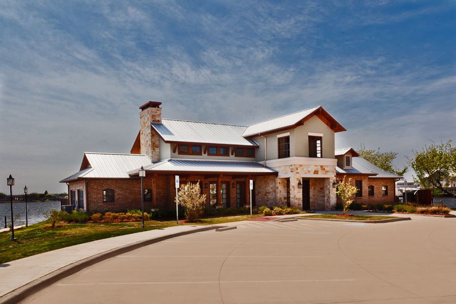 A large brick house with a chimney and landscaped surroundings under a clear blue sky.