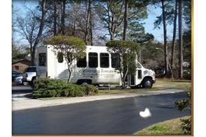 A shuttle bus parked on a road surrounded by trees.