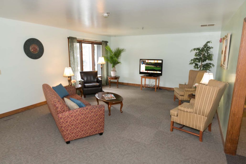 A spacious living room with a sofa, armchairs, and a television.