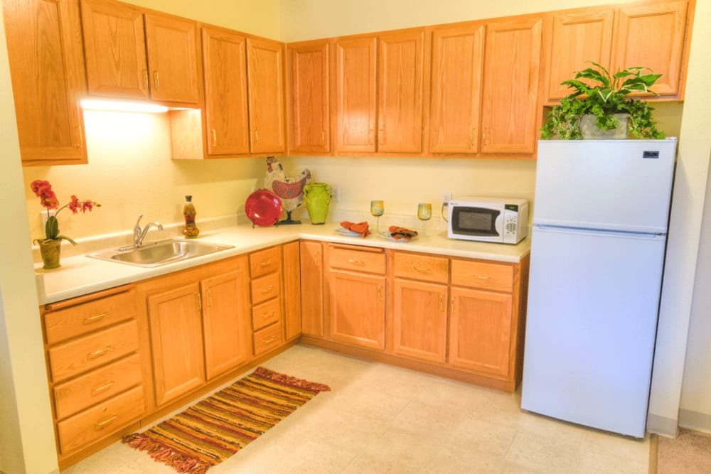 A well-lit kitchen with wooden cabinets, a white refrigerator, and various appliances.