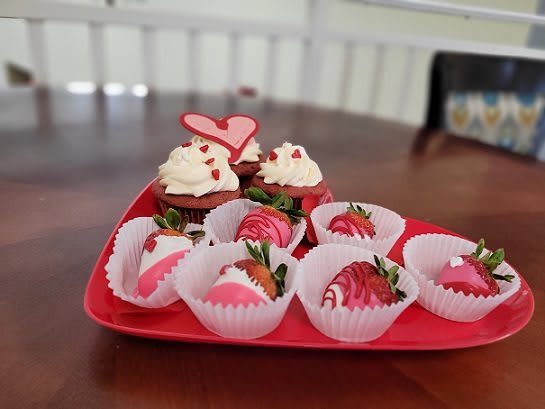 A tray with red velvet cupcakes and chocolate-covered strawberries, perfect for a sweet celebration.