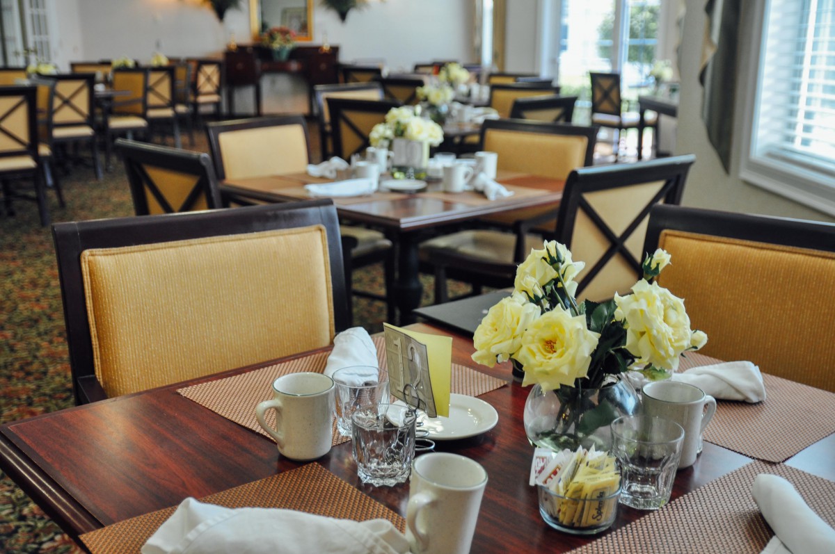 A beautifully set restaurant dining area with flowers on the tables.