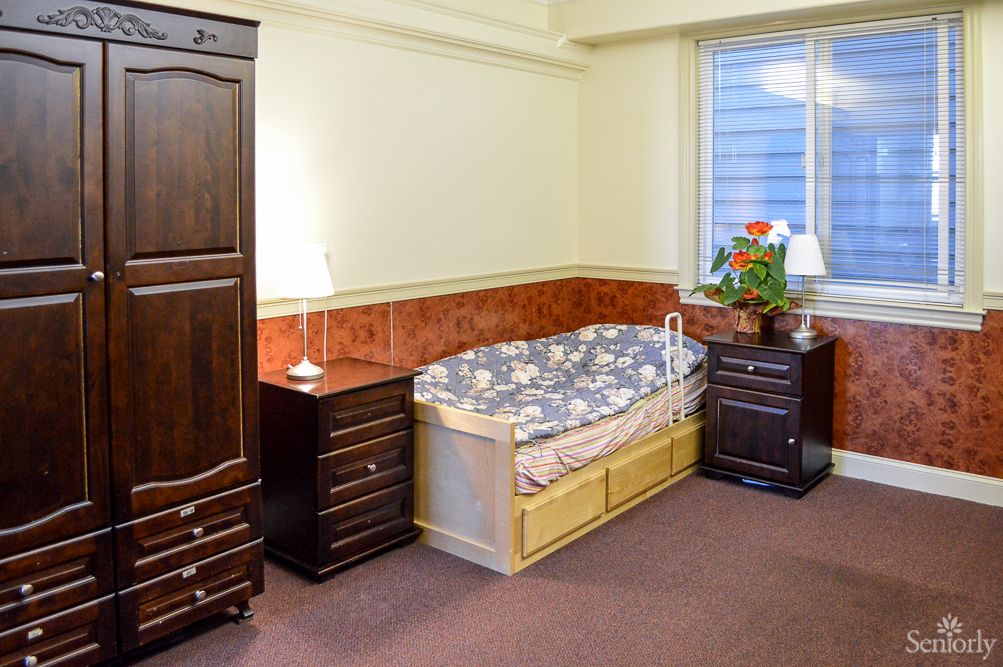 A cozy bedroom with a bed, wardrobe, nightstands, and a window with a flower pot.