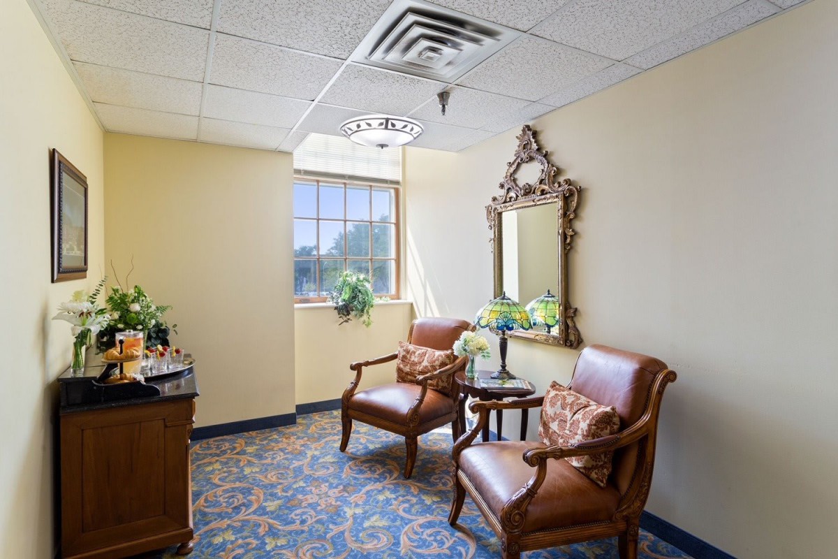A cozy waiting room with two armchairs, a decorative mirror, and natural light.