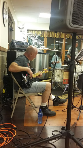 A bassist at band practice, focused on playing in a cozy indoor environment.