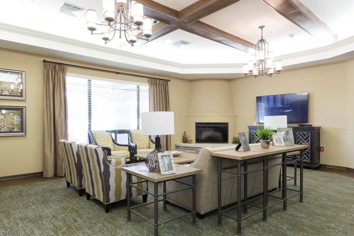 A cozy and elegantly designed living room with comfortable seating, a central chandelier, and a wall-mounted TV.