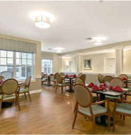 A well-lit dining room with neatly arranged tables and chairs.