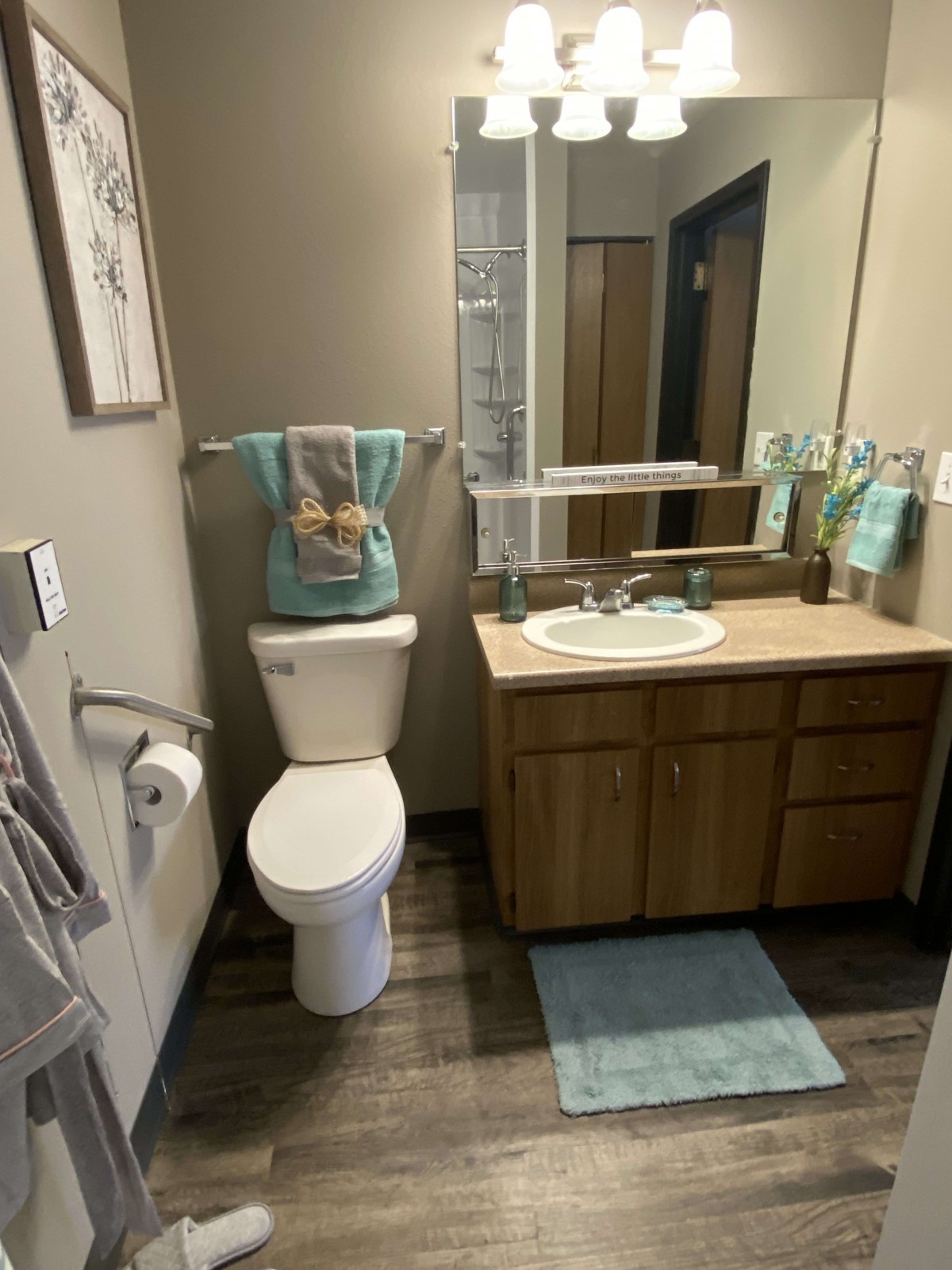 A neatly arranged bathroom featuring a toilet, sink with a mirror, and coordinated towels and floor mat.